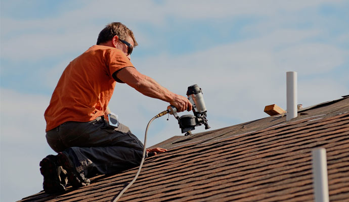 man-wears-orange-shirt-repairing-home-roof